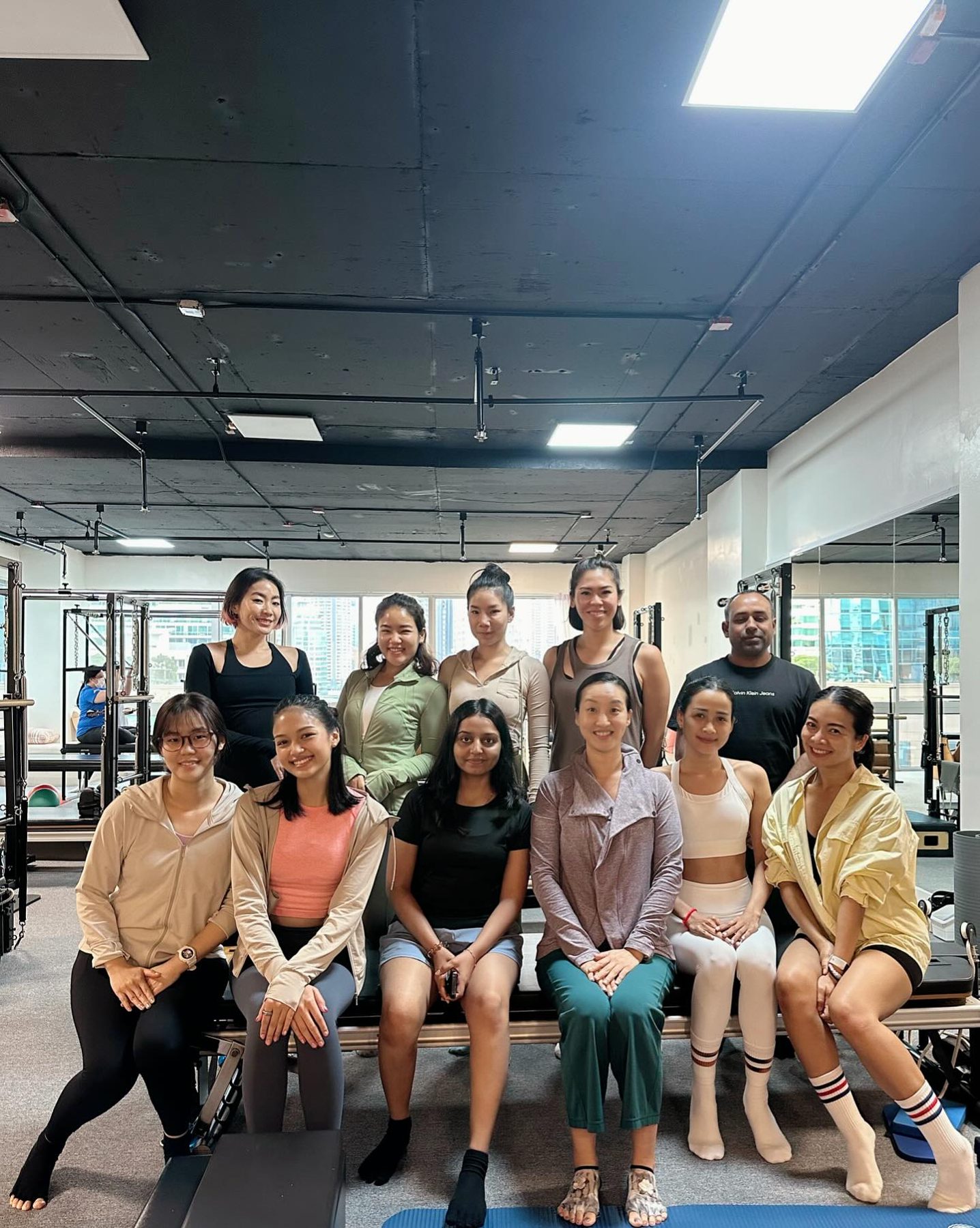 A group class seated on the reformers, relaxed after the session